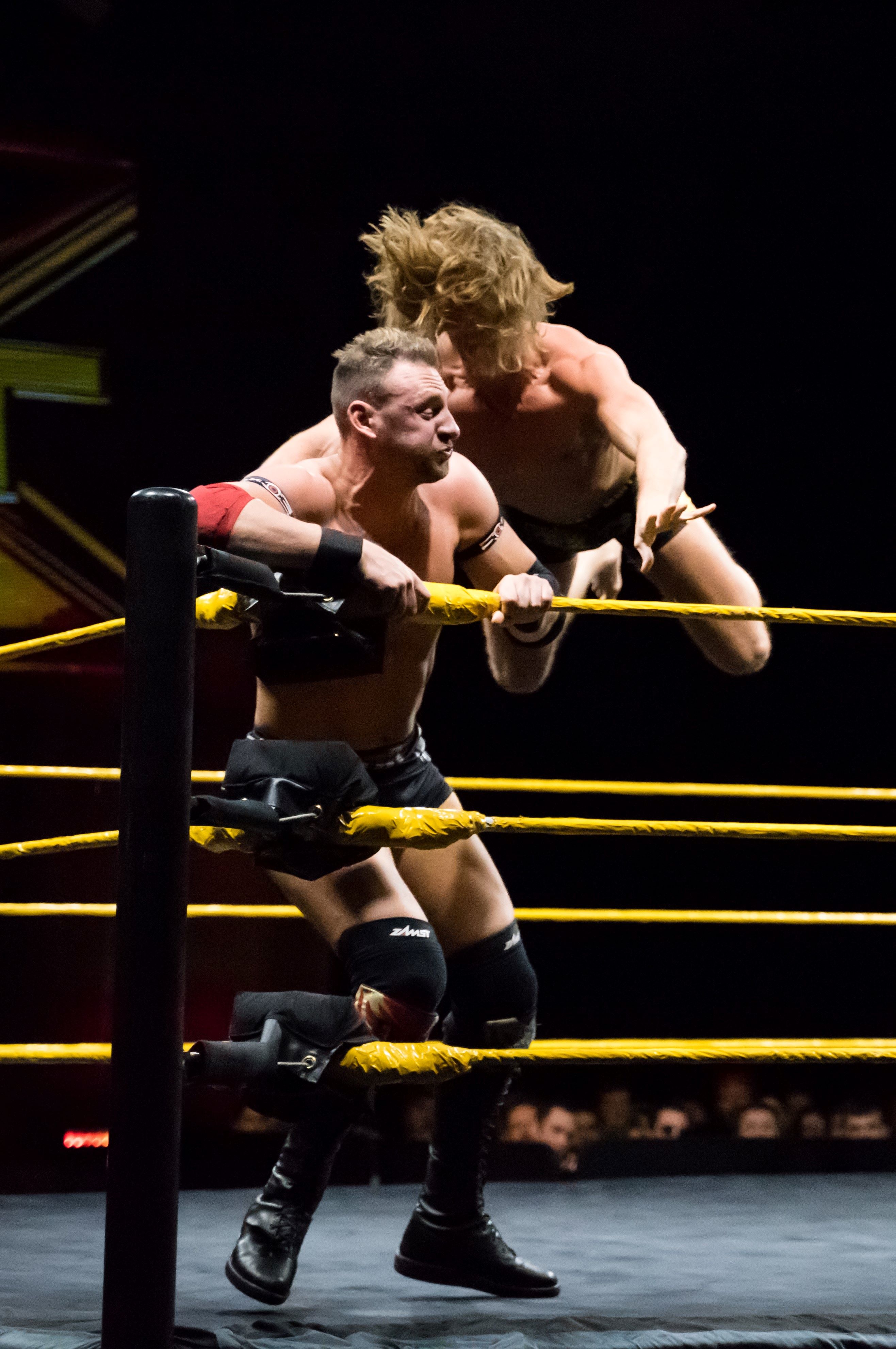 Two wrestlers in the corener of the wring.