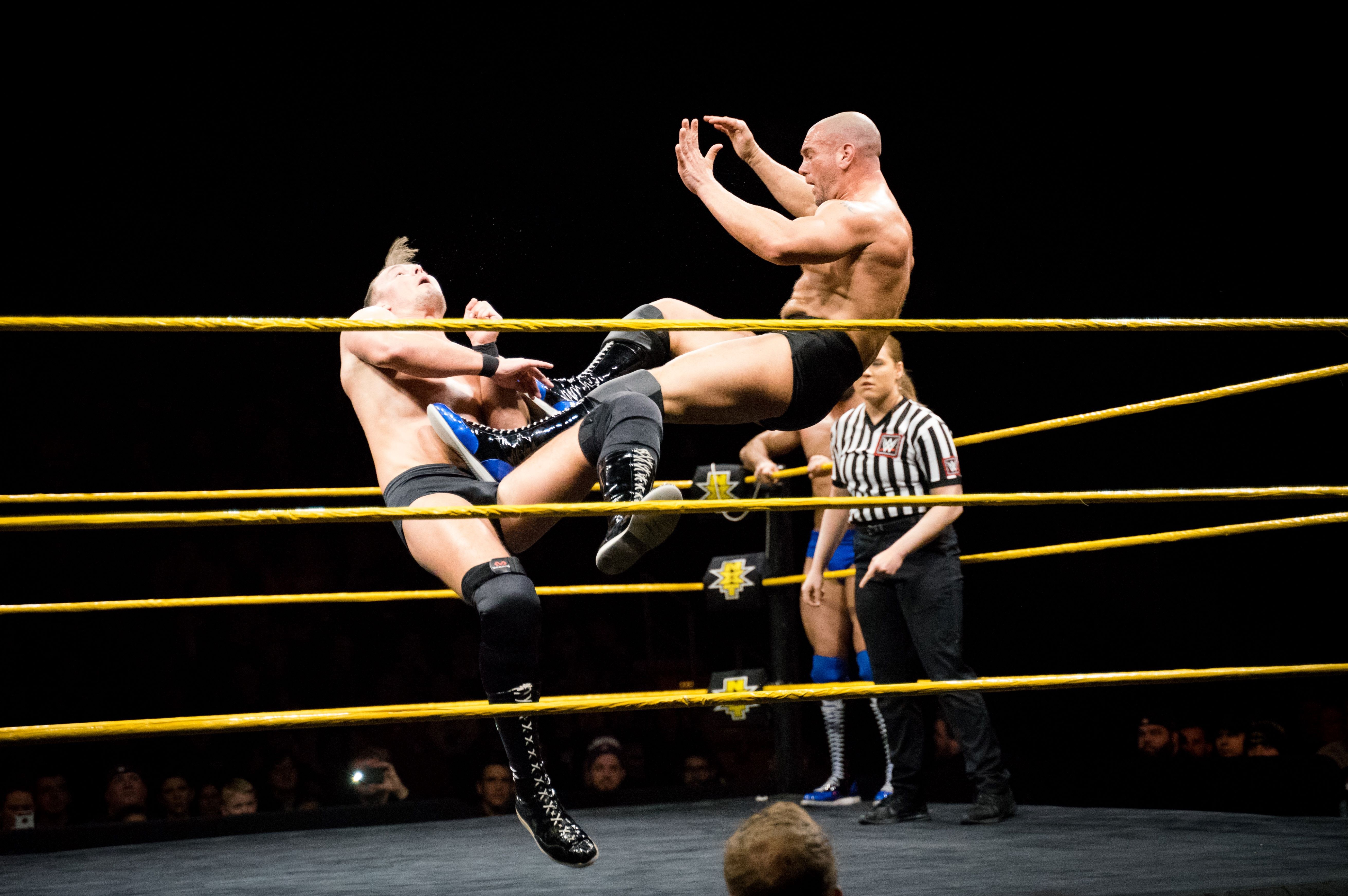 Wrestler performing flying kick on other wrestler.